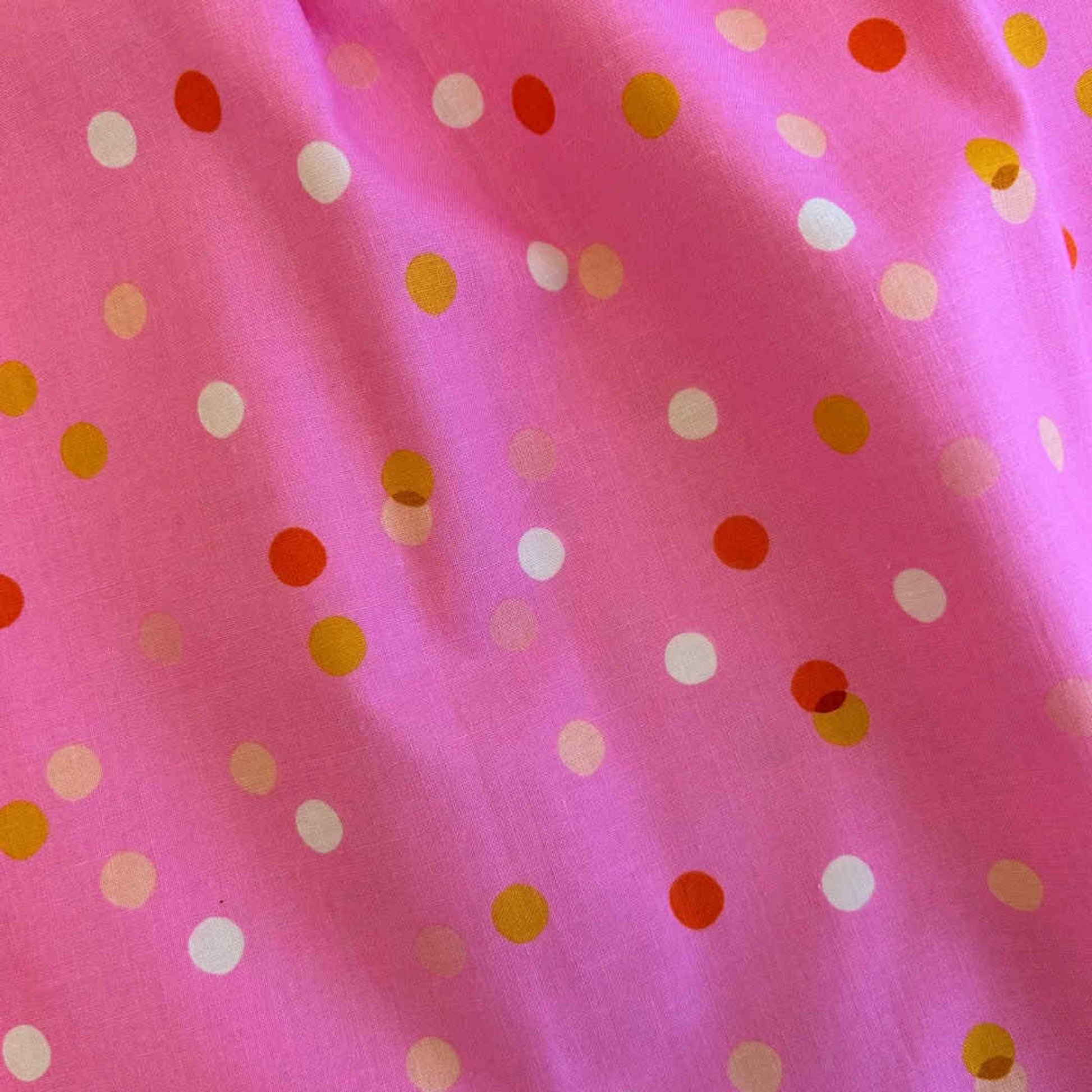 Pink fabric with colorful polka dots
