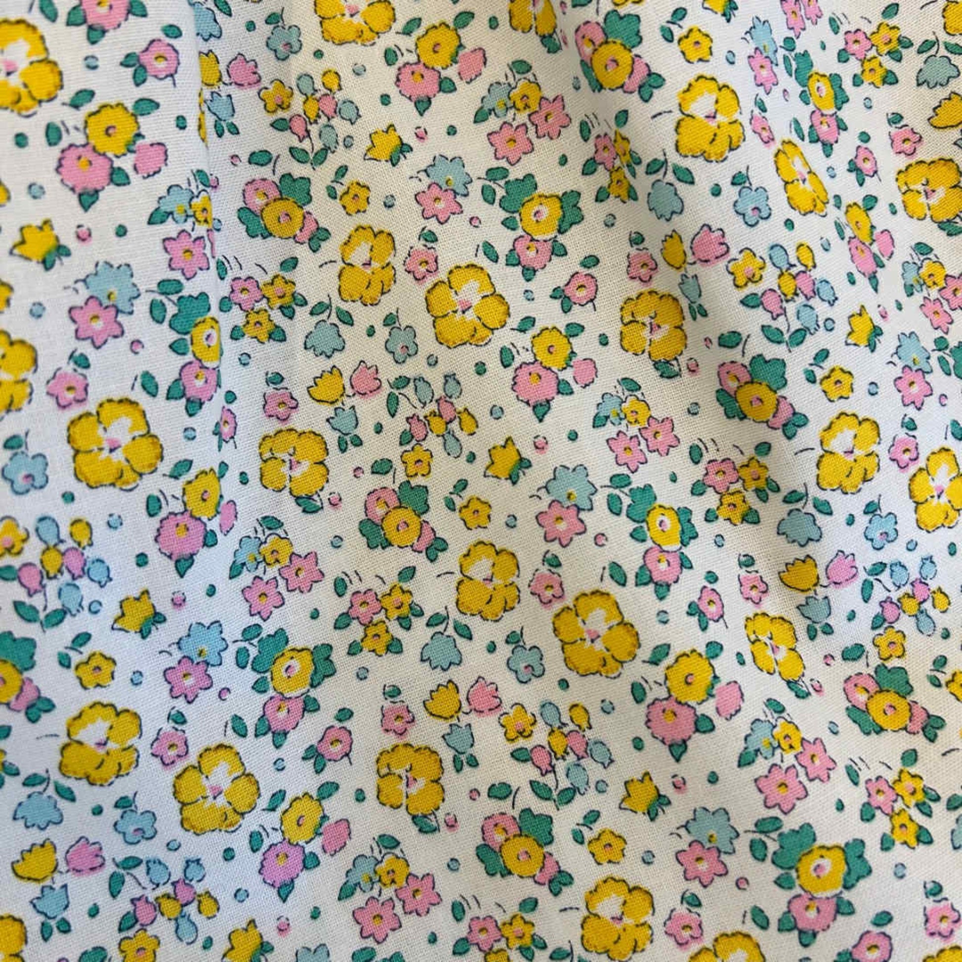 Floral patterned fabric with small flowers in yellow, pink, and blue on a white background.