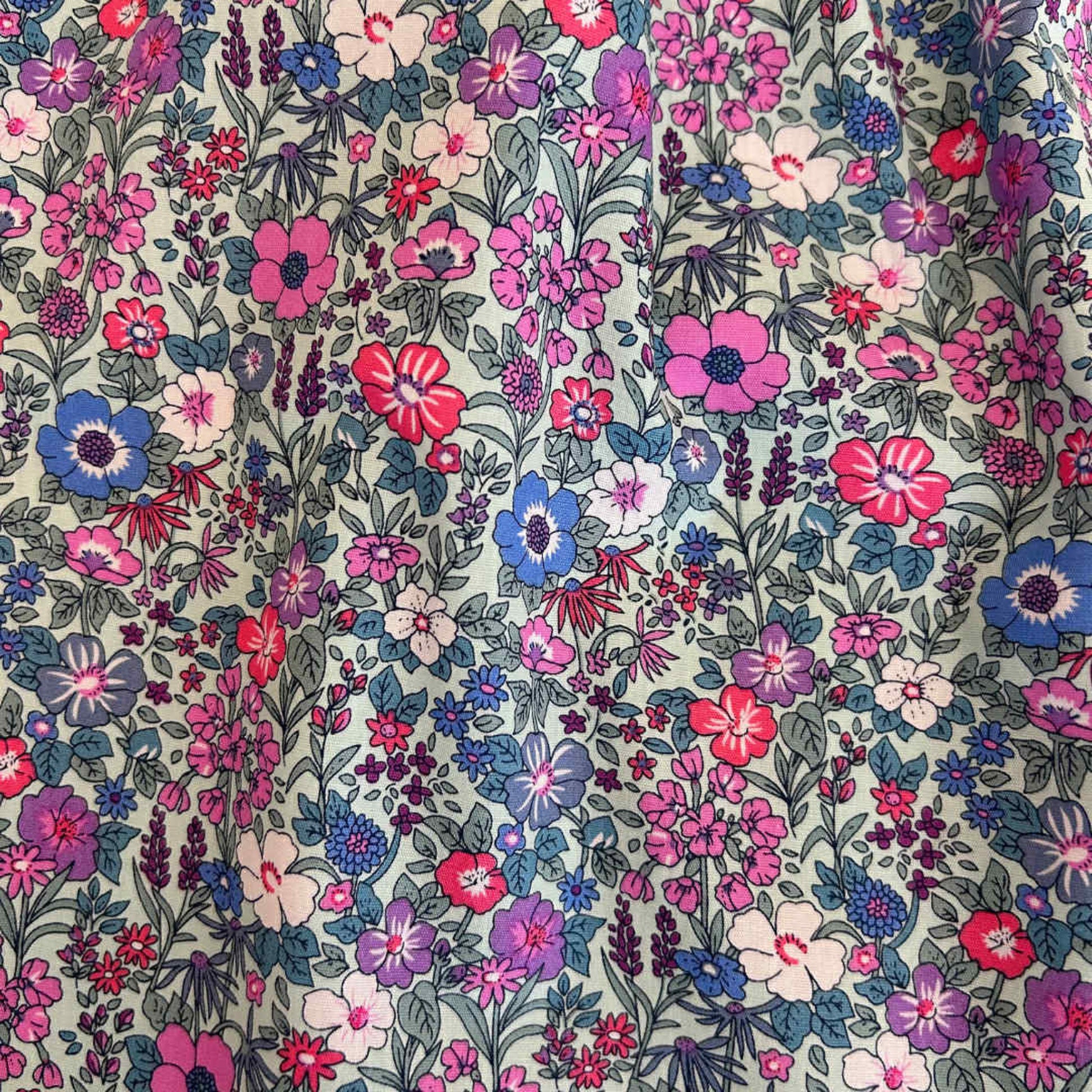 Floral pattern with pink, purple, and blue flowers on a green background